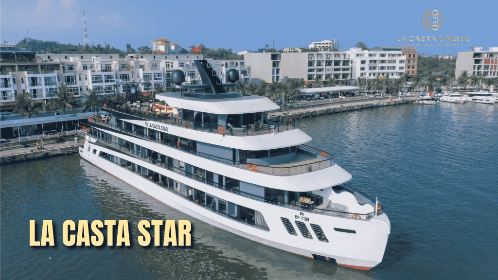 A panoramic aerial shot capturing the official launch of the La Casta Star luxury cruise, a grand 5-deck white and brown vessel, gliding gracefully through the calm, emerald waters of Lan Ha Bay at dawn on June 1st.